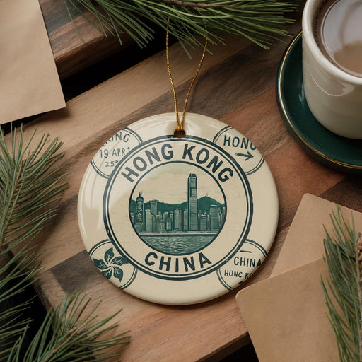 A decorative ornament featuring the image of Hong Kong, surrounded by pine branches and a cup of coffee on a wooden surface.