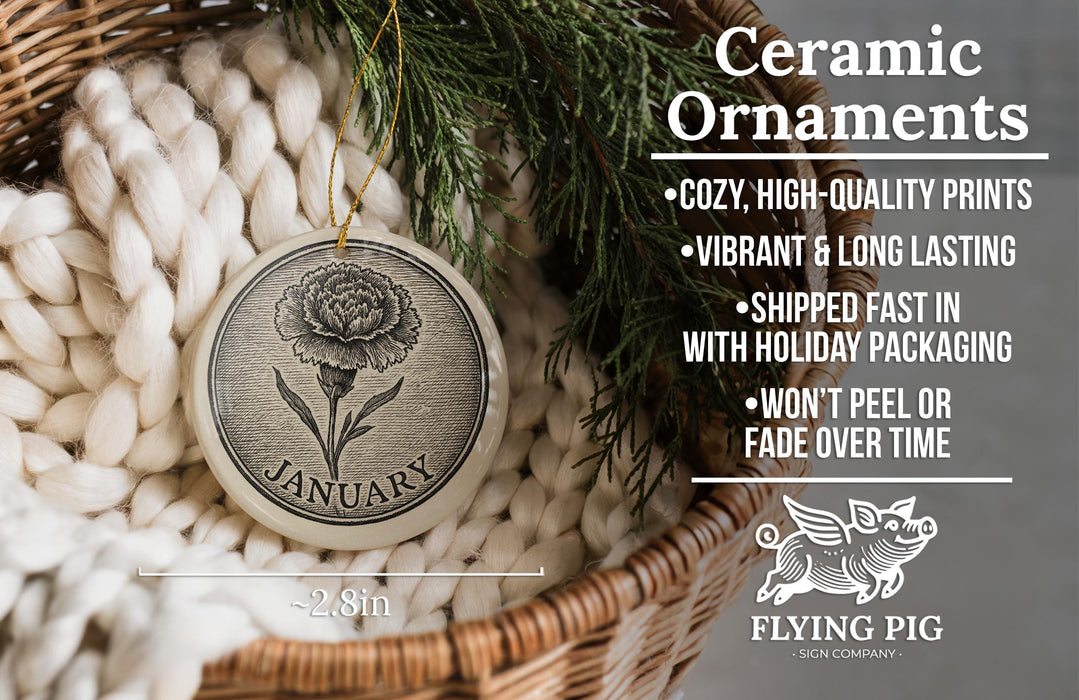 Ceramic ornaments, including a round ornament with a flower design, are displayed in a basket with a pine branch.