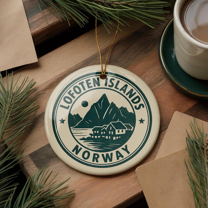 A circular ornament with the text "Lofoten Islands Norway" on it, surrounded by pine branches and a cup of coffee on a wooden surface.
