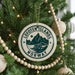 A Christmas tree decorated with ornaments, including a circular ornament with the text "Lofoten Islands NORWAY" and a wooden bead decoration.