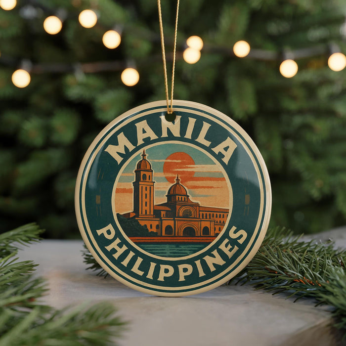 A round ornament with the text "MANILA PHILIPPINES" and an illustration of a building, likely representing the Manila skyline, is displayed in front of a Christmas tree with twinkling lights.