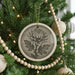 A Christmas tree decorated with ornaments, including a large chrysanthemum orchid ornament, wooden beads, and other ornaments.