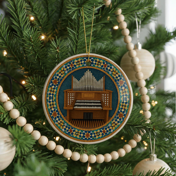 A Christmas tree decorated with ornaments, including a circular ornament featuring a wooden organ and a beaded garland.