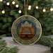 A circular ornament featuring an organ with pipes and a decorative border, hanging on a string and surrounded by pine branches with lights in the background.