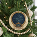 A Christmas tree decorated with ornaments, including a circular ornament with a starry night sky design and the word "Pleiades" written on it.