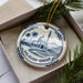 A decorative ornament featuring a mosque and palm trees, with the text "Salalah-Oman" around the edge.