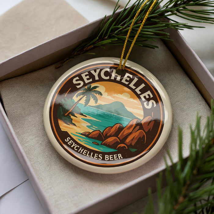 A decorative ornament in a box, featuring a tropical beach scene with palm trees and rocks, along with the text "SEYCHELLES BEER".