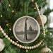 A Christmas tree decorated with ornaments, including a large circular ornament featuring a saxophone and a smaller circular ornament with a ball.