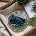 A decorative ornament in a box, featuring a telescope and a starry night sky design.