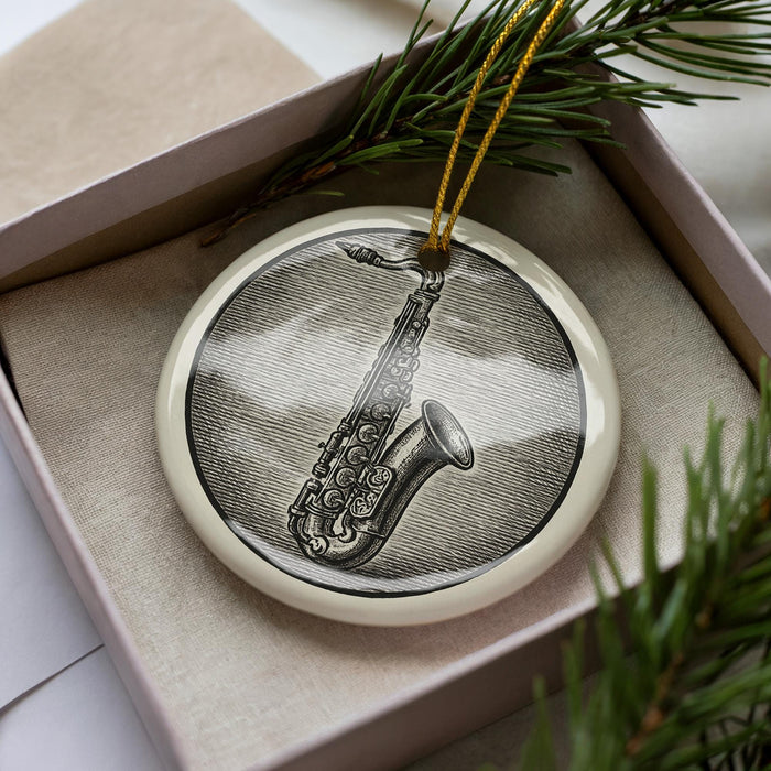 A ceramic ornament in the shape of a saxophone, displayed in a box with pine branches.