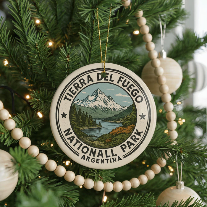 A round ornament on a Christmas tree, featuring the text "TERRA DEL FUEGO NATIONAL PARK ARGENTINA" and a mountain landscape.