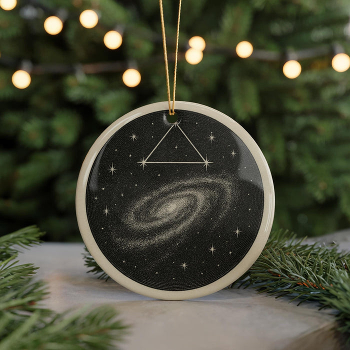 A circular ornament with a black background and a spiral galaxy design, hanging from a string.