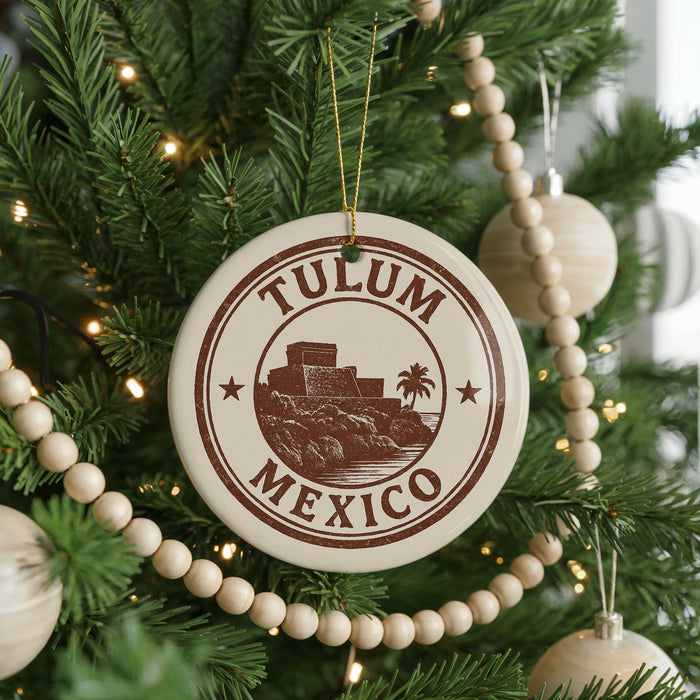 A Christmas tree decorated with ornaments, including a circular ornament with the text "TULUM MEXICO" and a palm tree illustration.