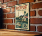 A vintage-style metal sign with the text "FREEPORT NEW YORK" and an illustration of a boat on a river, mounted on a brick wall.