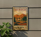 A vintage-style postage stamp depicting a scenic landscape of San Marcos, California, with mountains, buildings, and trees.