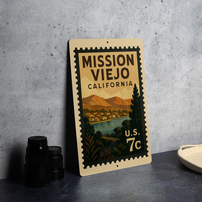 A vintage-style metal sign with a postage stamp design, featuring a scenic landscape of mountains, trees, and a river, along with the text "MISSION VIENJO CALIFORNIA" and "U.S. 7c".