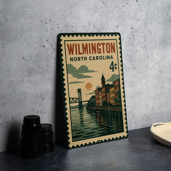 A metal sign with a vintage design depicting a cityscape and a bridge, placed on a table next to some black camera lenses.