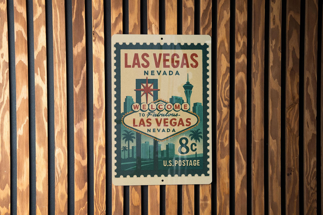 A vintage-style metal sign that reads "Welcome to Fabulous Las Vegas Nevada" and features a postage stamp design, mounted on a wooden wall.