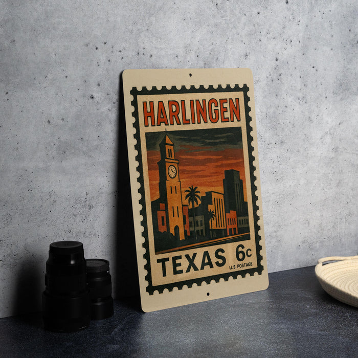 A vintage postage stamp from Harlingen, Texas, featuring a cityscape with a clock tower and palm trees, placed on a table next to some black camera lenses.