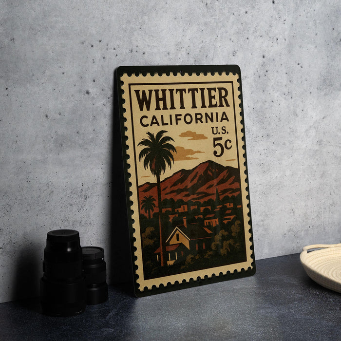 A vintage postage stamp from California, featuring a palm tree and mountains, is displayed on a table.