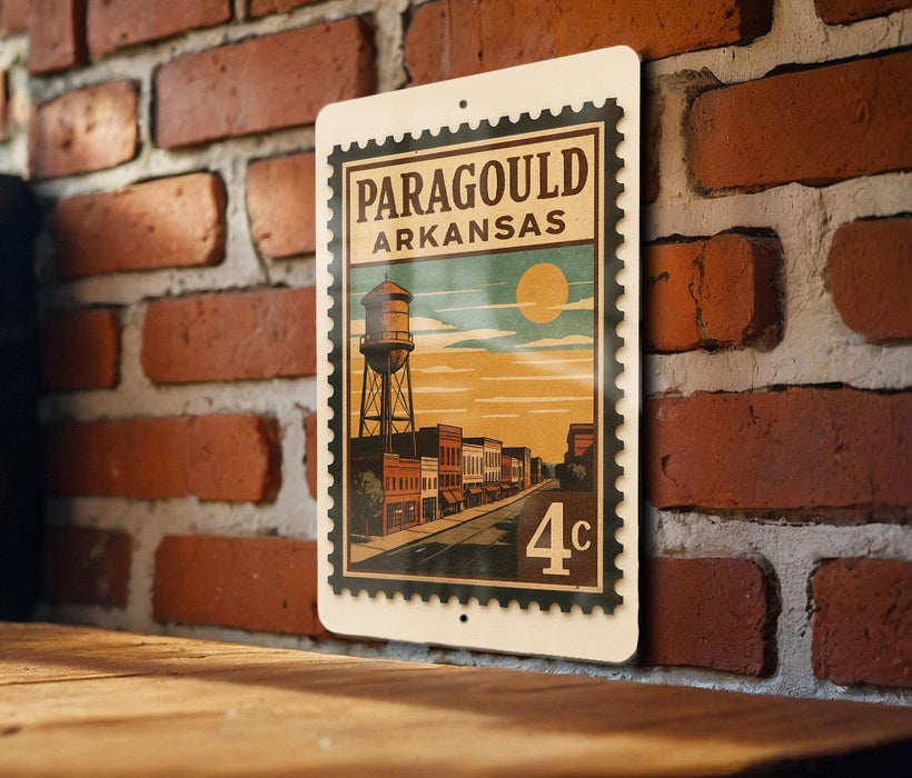 A vintage-style metal sign with the text "Paragould ARKANSAS" and an illustration of a water tower, mounted on a brick wall.