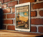 A vintage-style metal sign with the text "Paragould ARKANSAS" and an illustration of a water tower, mounted on a brick wall.