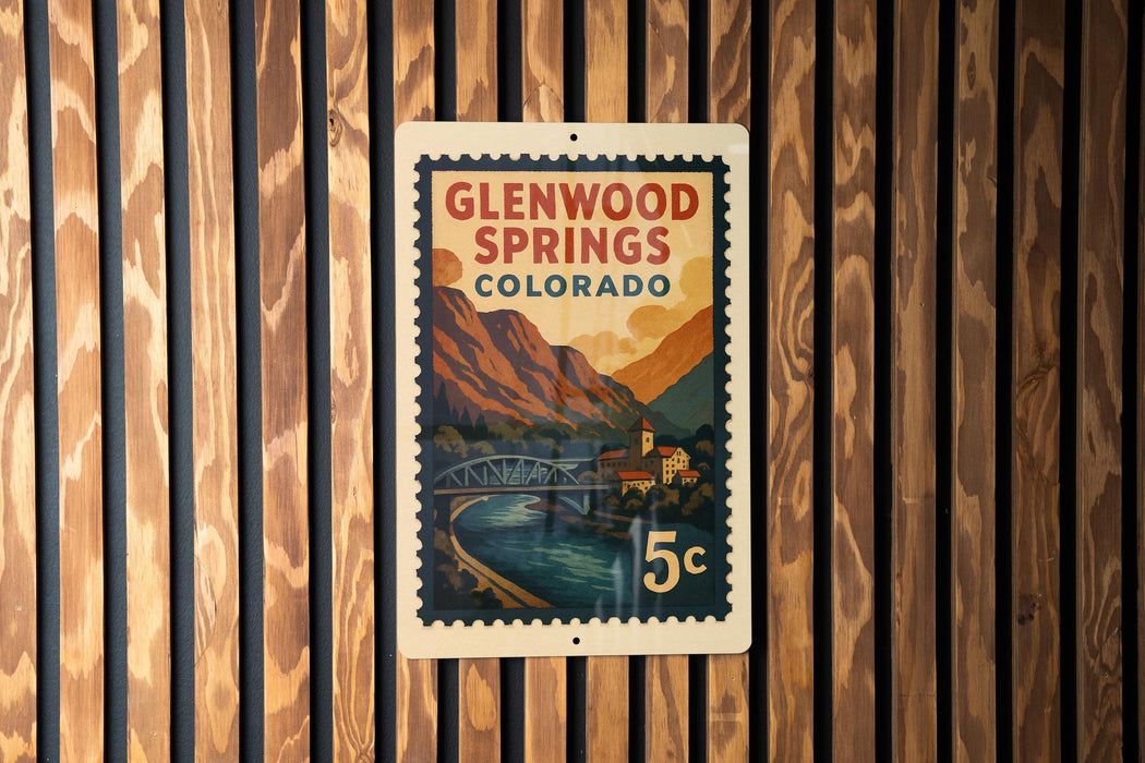 A vintage Glenwood Springs, Colorado postage stamp is displayed on a wooden wall.