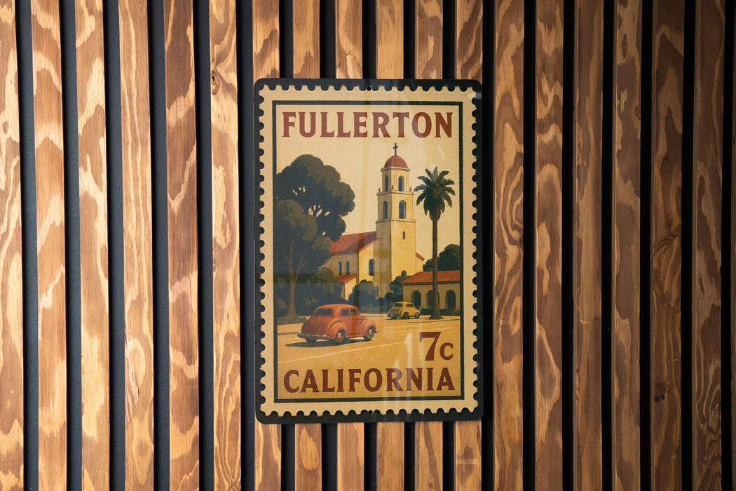 A vintage postage stamp from California featuring a car and a bell tower, mounted on a wooden wall.