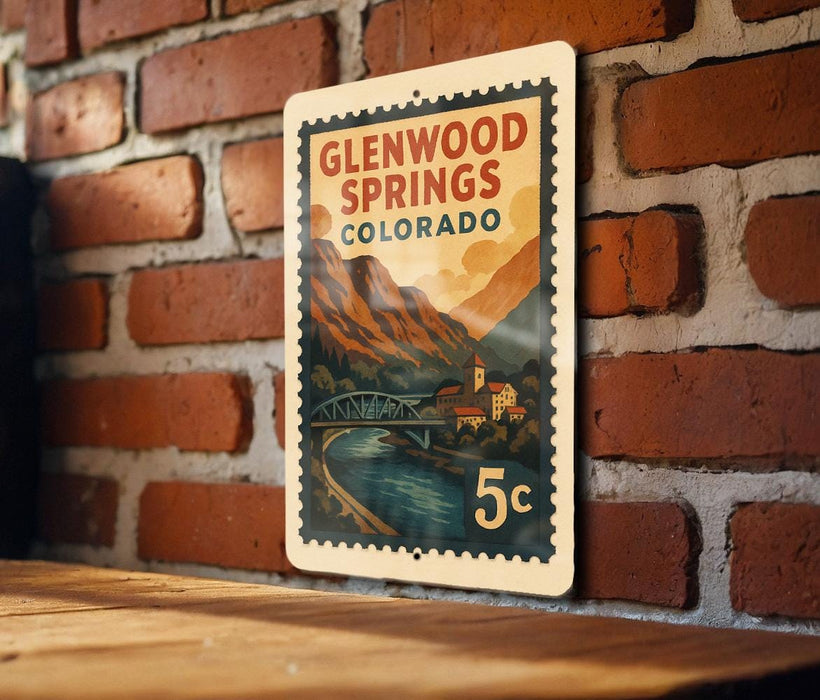 A vintage-style postage stamp depicting Glenwood Springs, Colorado, with a scenic mountain landscape and a bridge.