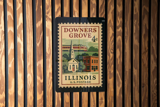 A vintage postage stamp from Illinois, featuring a church and a train, is displayed on a wooden wall.