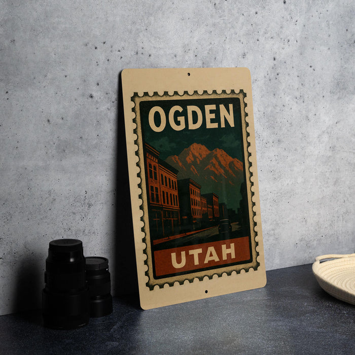 A vintage-style stamp depicting a cityscape with mountains in the background, featuring the text "OGDEN" and "UTAH" prominently displayed.