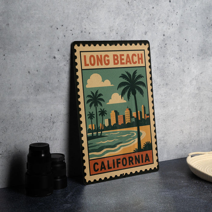 A vintage-style metal sign with a beach scene and palm trees, featuring the text "LONG BEACH" and "CALIFORNIA" on it, is displayed on a table.