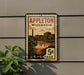 A vintage postage stamp from Wisconsin, featuring an illustration of a cityscape with a waterfall, mounted on a wall.