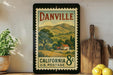 A framed vintage postage stamp depicting a rural landscape in California, with a house and trees in the background.