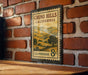 A vintage postage stamp from the United States, featuring a scenic landscape of hills and mountains, is displayed on a brick wall.