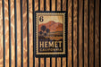 A California postage stamp with the number 6 on it, displayed on a wooden wall.