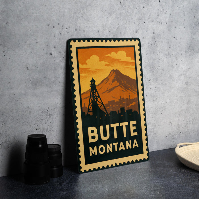 A vintage-style metal sign with a mountain and a tower in the background, along with the text "BUTTE MONTANA" prominently displayed.