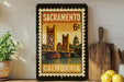 A framed vintage postage stamp from Sacramento, California, featuring the iconic Golden Gate Bridge and the state's capitol building.