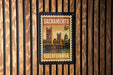 A framed California postage stamp featuring the Golden Gate Bridge, mounted on a wooden wall.