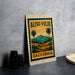 A framed poster of a scenic landscape with palm trees and mountains, featuring the text "ALISO VIEJO CALIFORNIA" on the poster.