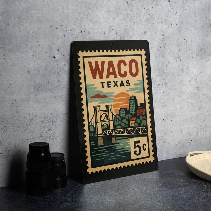 A framed poster of Waco, Texas, featuring a bridge and sunset, is displayed on a table.