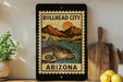 a framed poster of a fish with the text "Bullhead City Arizona" on it, placed on a shelf next to a wooden cutting board and some lemons.