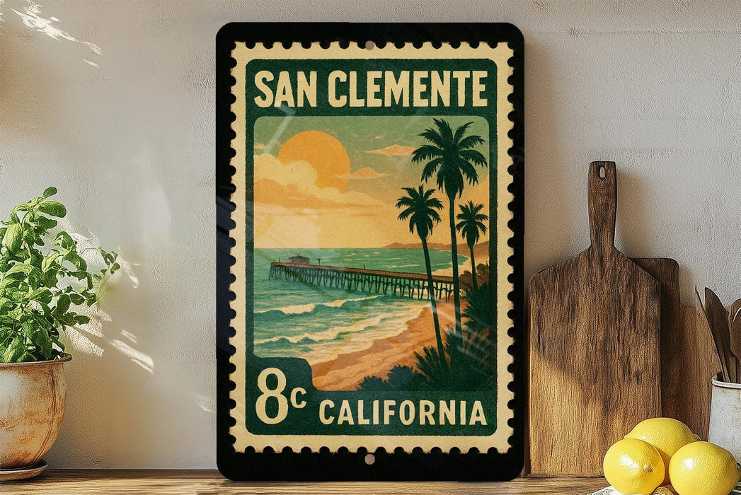 A framed vintage postage stamp depicting a beach scene with a pier and palm trees, placed on a shelf next to a wooden cutting board and a potted plant.