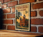 A vintage postage stamp from Alabama, featuring a brick building and a tree, is displayed on a brick wall.