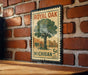 A vintage-style postage stamp featuring a tree and a store, mounted on a brick wall.