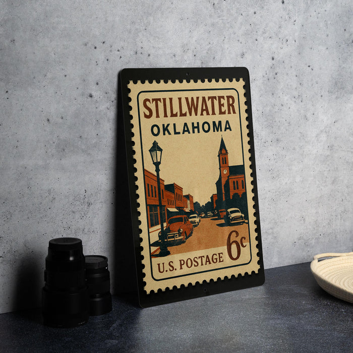 A vintage postage stamp from Stillwater, Oklahoma, featuring an illustration of a street scene with buildings and cars.