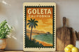 A vintage-style postage stamp depicting a beach scene with palm trees and a pier, hanging on a wall next to a wooden cutting board and a potted plant.