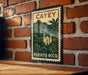 A vintage-style metal sign with a tropical island landscape and a church, mounted on a brick wall.