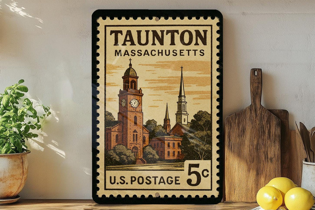 A framed vintage postage stamp from Massachusetts, depicting a church and other buildings, is displayed on a shelf next to a wooden cutting board and some lemons.
