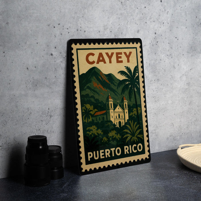 A vintage-style postage stamp depicting a tropical landscape with a church and palm trees, placed on a gray countertop next to some black camera lenses.